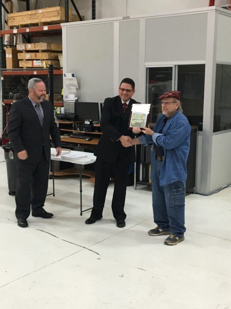 Photo of pilot receiving award, presented by two representatives of the FAA